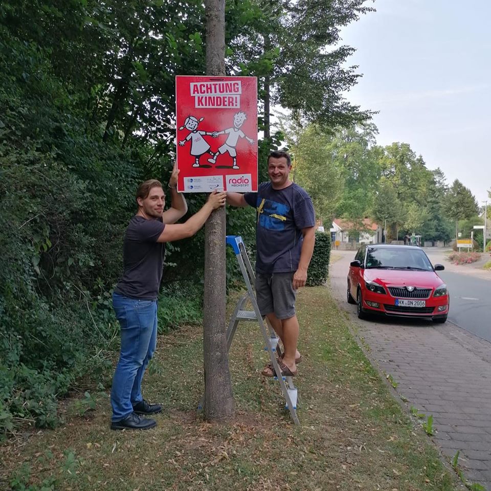 Zwei Männer hängen ein Plkat auf